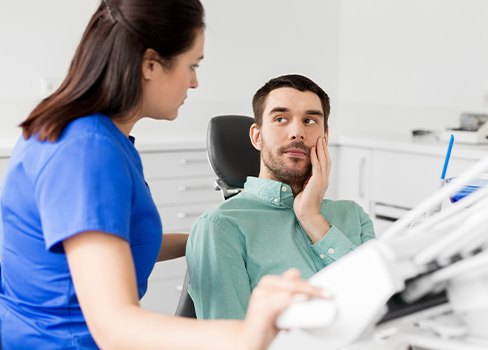 Man in dental chair holding jaw