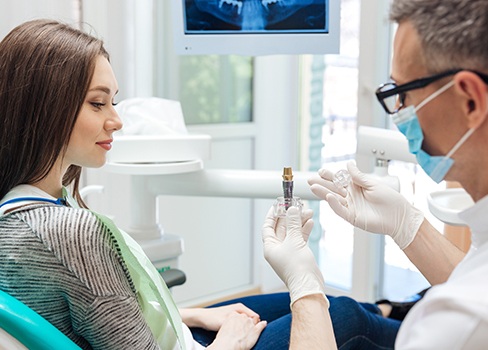 Dentist showing patient dental implant model