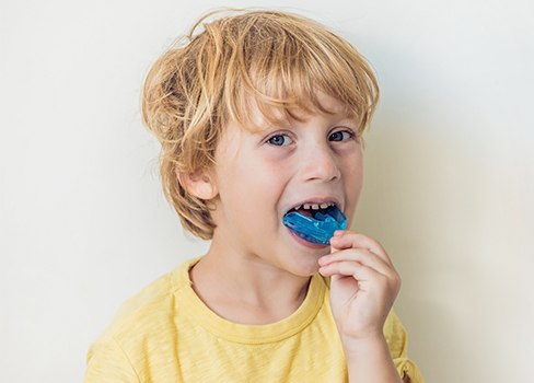 Child placing blue mouthguard