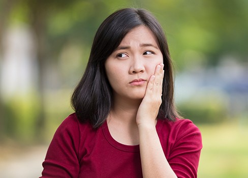  mladá žena v bolesti držící čelist