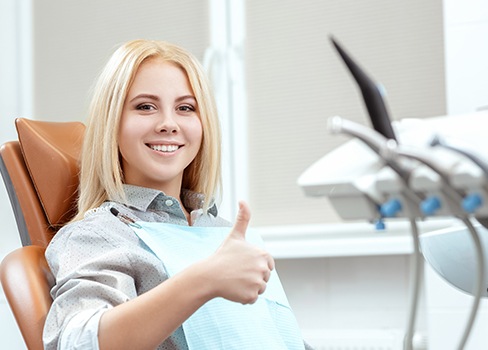 Woman in dental chair giving thumbs up