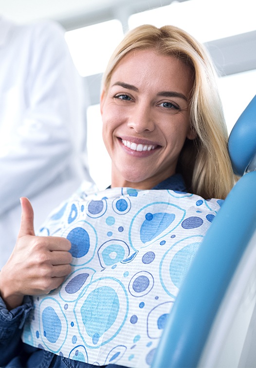 Woman in dental chair giving thumbs up