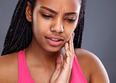 Young woman holding cheek in pain